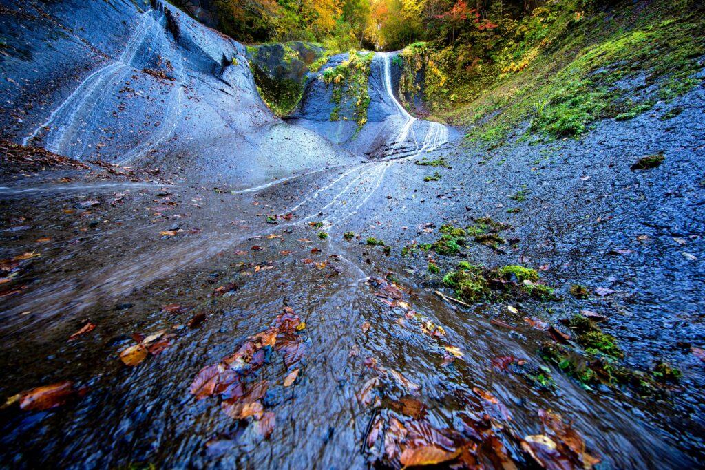 Beautiful autumn waterfall with vibrant foliage in Takayama, Japan.